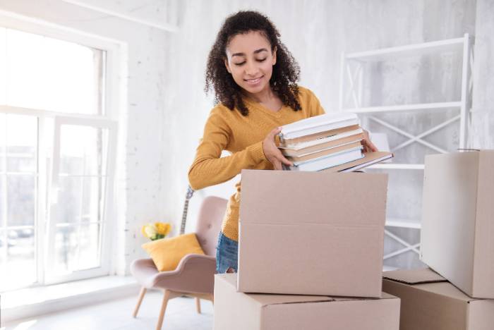 female student unpacking boxes in a sunny room